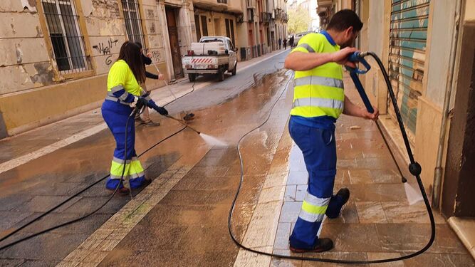 Operarios limpian el barro de una calle de Málaga.