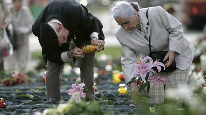 Unos ancianos ponen flores en las tumbas de Katyn.