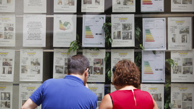 Dos personas miran el escaparate de una inmobiliaria en Málaga.