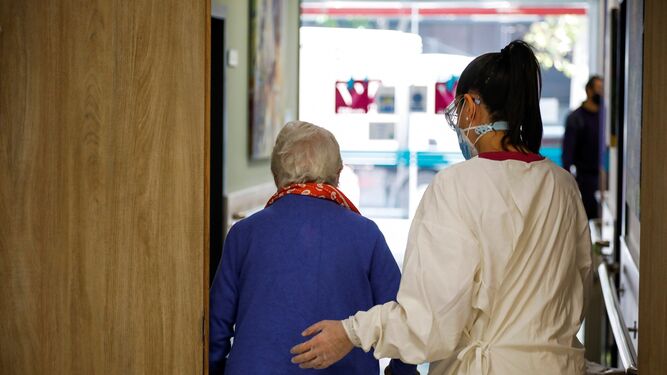 Una enfermera acompaña a una persona mayor en un hospital durante la pandemia.