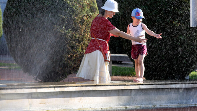 Una mujer y un niño juegan en la fuente.
