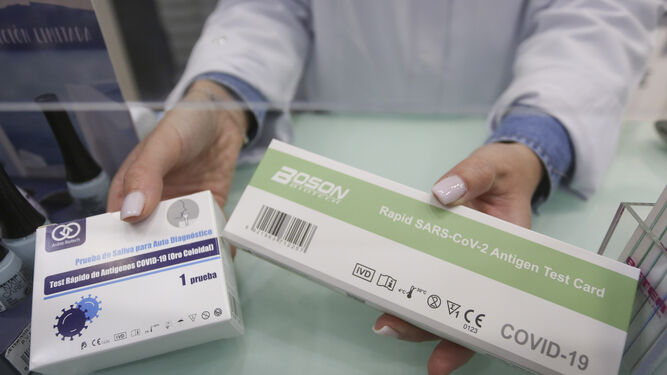 Una farmacéutica muestra cajas de test de antígenos.