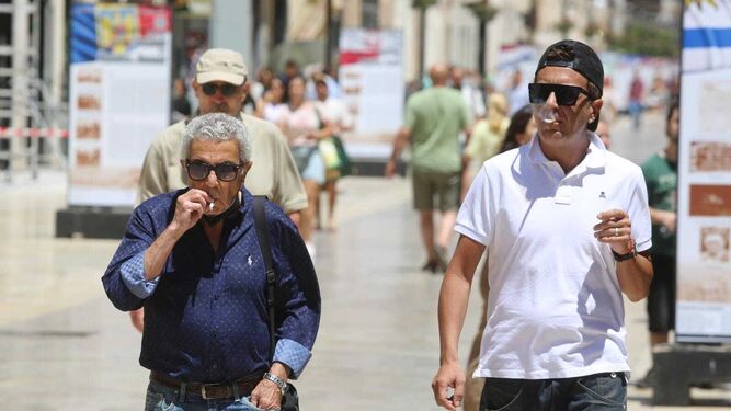 Dos hombres fumando mientras pasean por calle Larios.