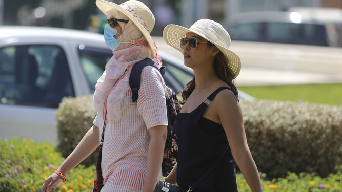 Dos mujeres se protegen del sol en Málaga con sombreros.