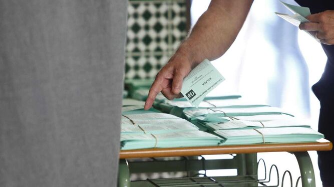 Una persona busca entre distintas papeletas en un colegio electoral.