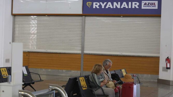 Una pareja espera sentada a las puertas de un mostrador de Ryanair.