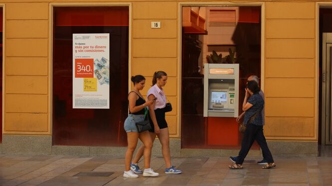Varias personas pasan junto a una oficina bancaria en Málaga.