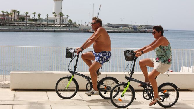 Dos turistas pasean con sus bicicletas por el Puerto de Málaga.