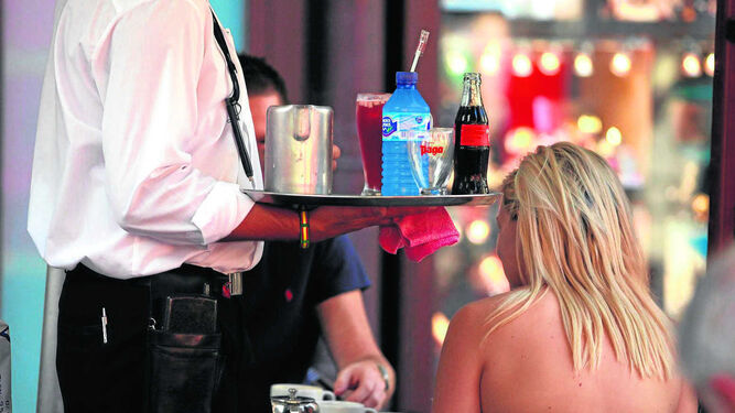 Un camarero  sirve unas bebidas en un bar.