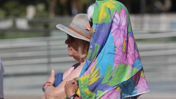Dos turistas se protegen la cabeza del sol con sombrero y pañuelo.