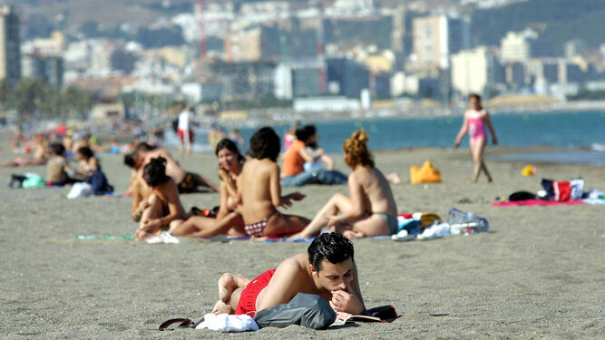 Un joven lee un libro en la playa de La Misericordia de Málaga.