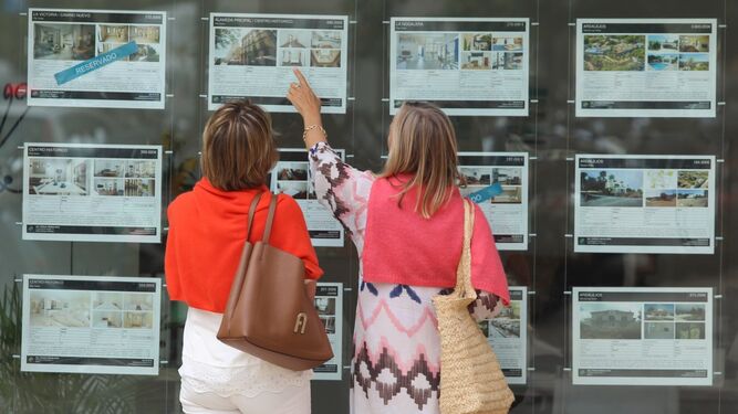 Dos mujeres consultan un anuncio en una inmobiliaria.