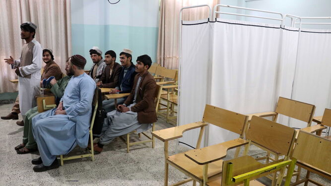 Estudiantes varones reciben clase junto a las sillas vacías destinadas a las alumnas en un instituto de Kandahar.
