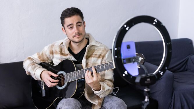 Adrián Campos, junto a su guitarra, grabándose para Tik Tok.