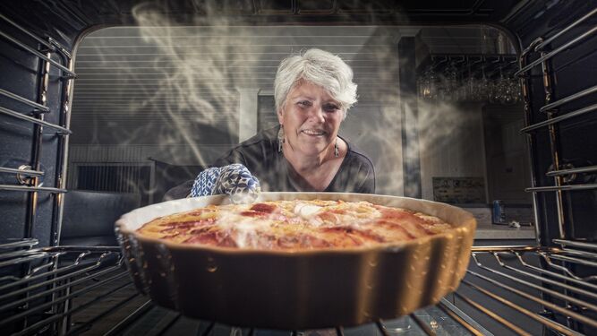 Una mujer saca del horno la tarta-flan para dejarla reposar