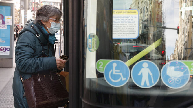 Una usuaria con mascarilla se dispone a entrar en un autobús urbano.