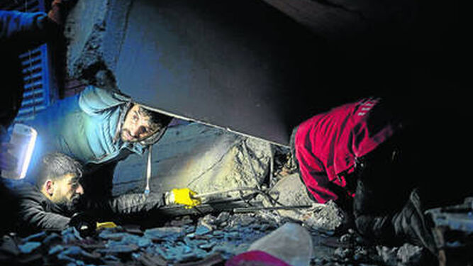 Varias personas intentan ayudar a las víctimas tras el derrumbe de un edificio por el terremoto en Diyarbakir, Turquía.