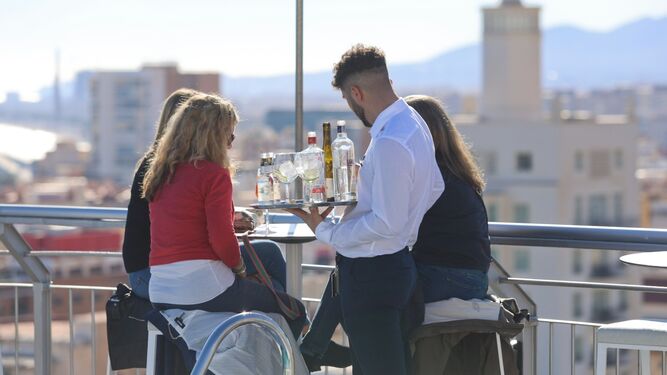 Un camarero sirve copas en una terraza de Málaga.