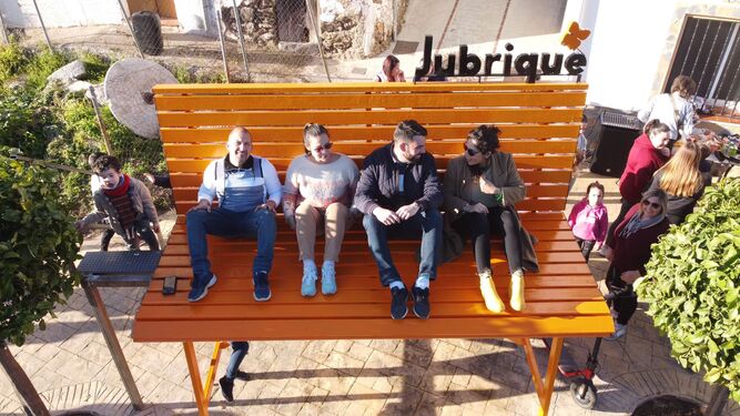 Varios vecinos sentados sobre el banco gigante de Jubrique.