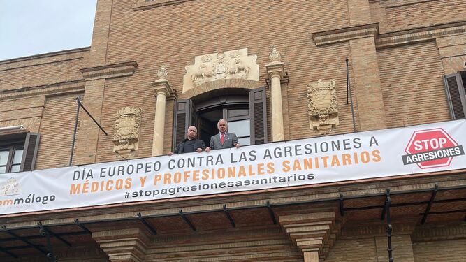 Navarro y Martín, junto al cartel desplegado en la sede del Colegio de Médicos de Málaga.