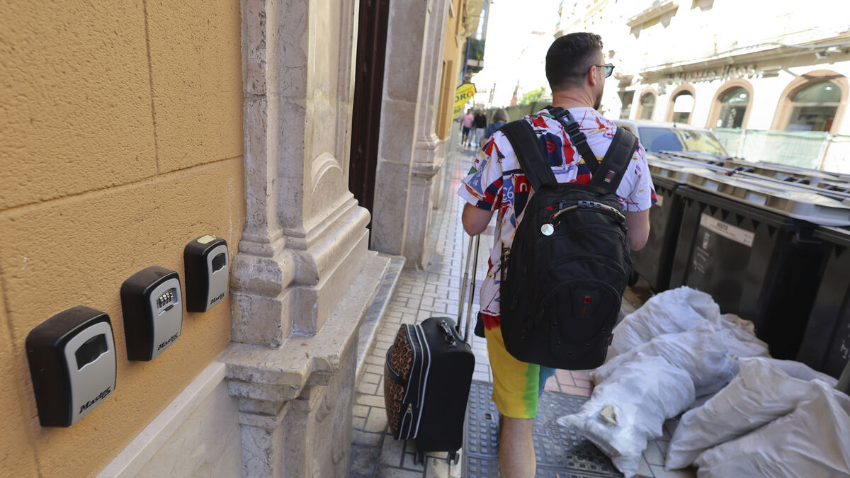 Un turista pasa entre cajetines para llaves y basura en calle Carretería.