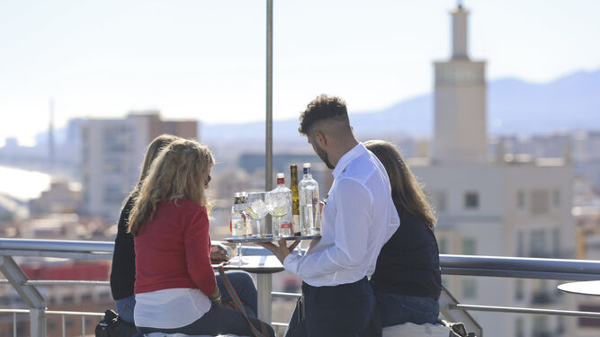 Un camarero atiende a unos clientes en la terraza de un hotel malagueño