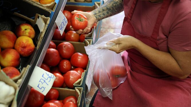Trabajadora de Frutas y Verduras Ángel preparando una bolsa de tomates.