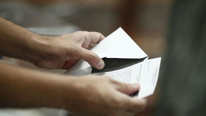 Una persona mete una papeleta de votación en un sobre