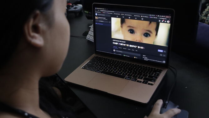 Una filipina embarazada muestra una página sobre adopciones.