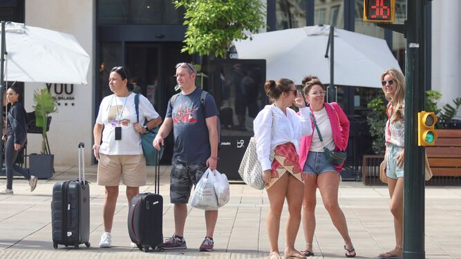Un par de turistas con maletas frente a un hotel en el centro de Málaga.