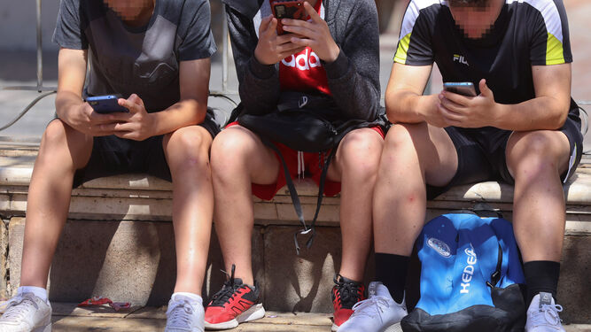 Jóvenes mirando sus móviles.