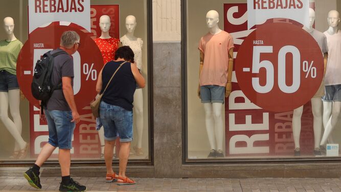 Una pareja mira un escaparate de una tienda en Málaga que anuncia descuentos.