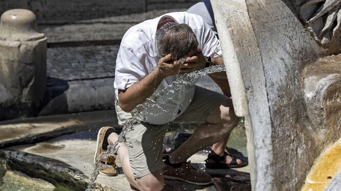 Un hombre se refresca en una fuente en Roma.