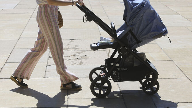 Una mujer llevando a un bebé en un carrito en Málaga.