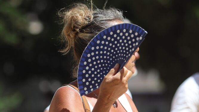 Un mujer se refresca con un abanico en una calle de Málaga