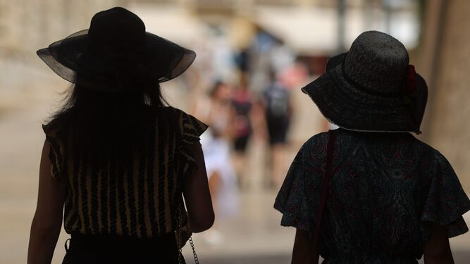 Dos mujeres caminan bajo la sombra en una céntrica calle de Málaga