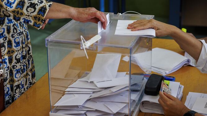Una mujer introduce su voto en una urna en un colegio electoral