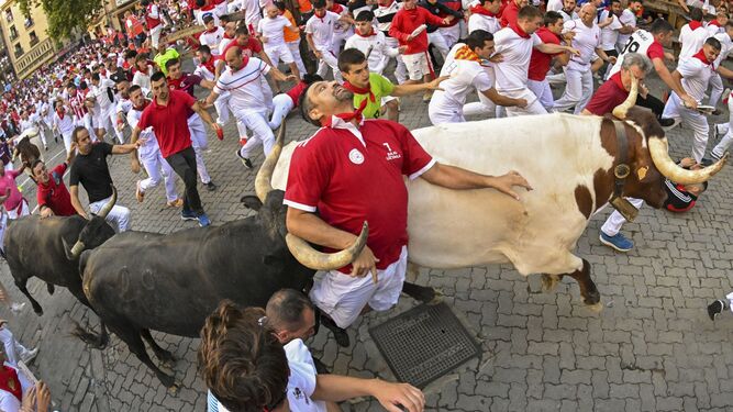 Un mozo entre dos toros en el octavo y último encierro de San Fermín.