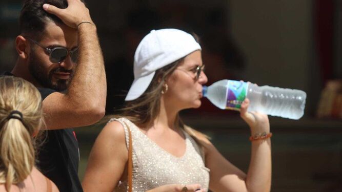 Una mujer bebe agua para sofocar el calor.