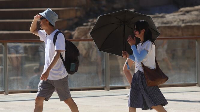 Dos visitantes se protegen del sol en la calle Alcazabilla, con paraguas incluido.