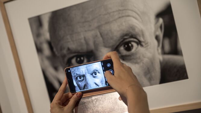 Una persona realiza una fotografía a un retrato de Picasso.