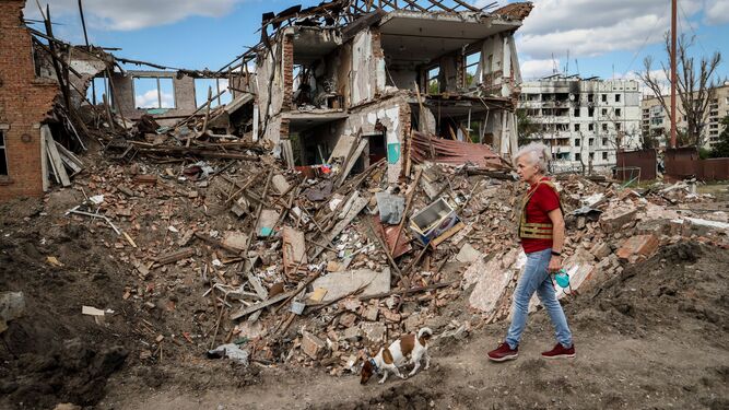 Una mujer y su perro camina junto a los restos de un colegio atacado por los rusos en Zaporiya