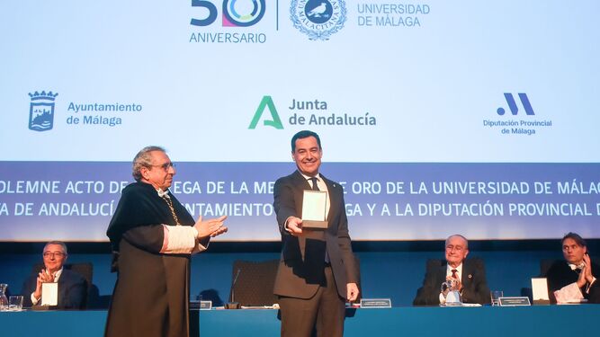 El presidente de la Junta, Juan Manuel Moreno, recibiendo la Medalla de Oro de manos del rector de la UMA, José Ángel Narvaéz.