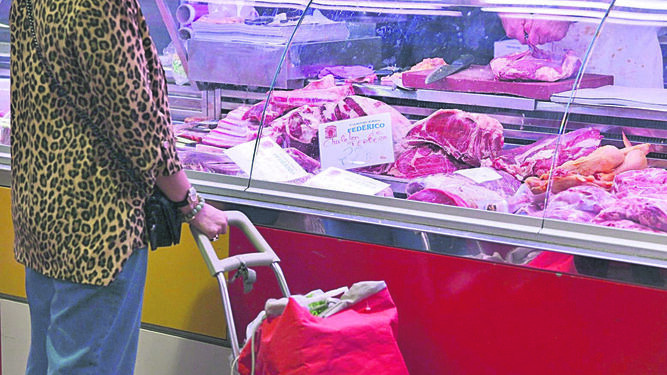Una mujer compra en una carnicería en el mercado.