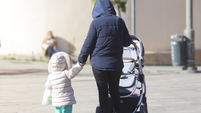 Una mujer pasea abrigada con una menor
