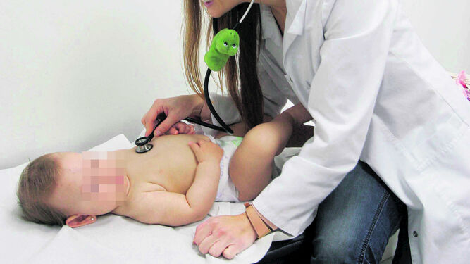 Una sanitaria ausculta a un bebé.