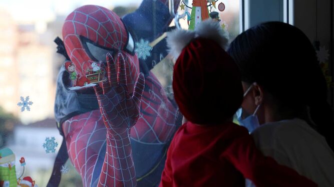 Una niña saludando a Spiderman en el Hospital Materno Infantil de Málaga.