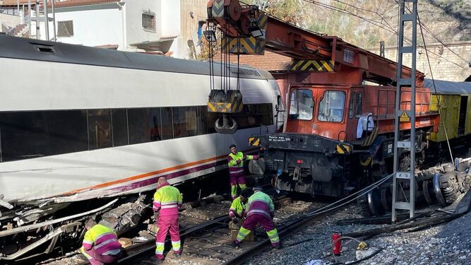 Trabajadores de Renfe este lunes, en la estación de el Chorro, junto a uno de los trenes accidentados.