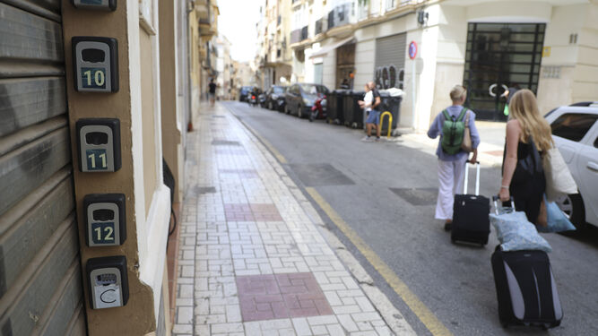 Dos turistas caminan frente a pisos turísticos en el centro de Málaga.