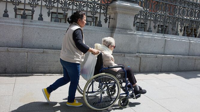 Una mujer mayor en silla de ruedas y su cuidadora.